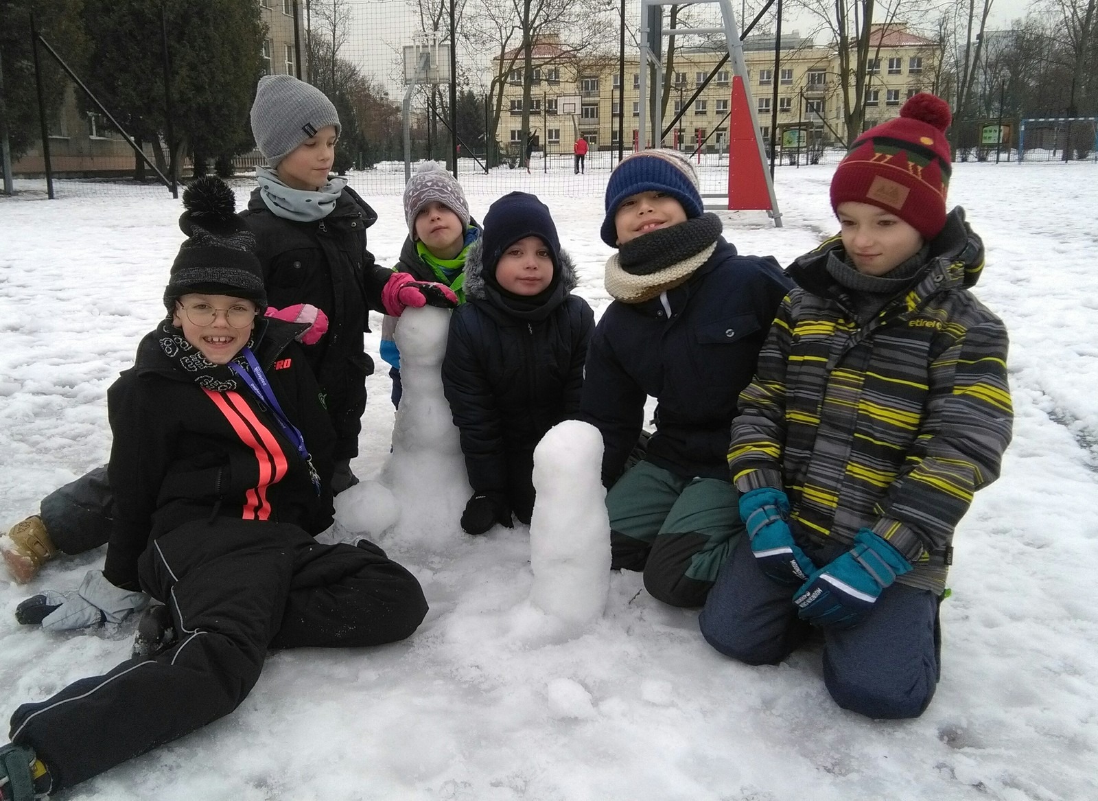 Dzieci z ulepionym  ze śniegu bałwanem