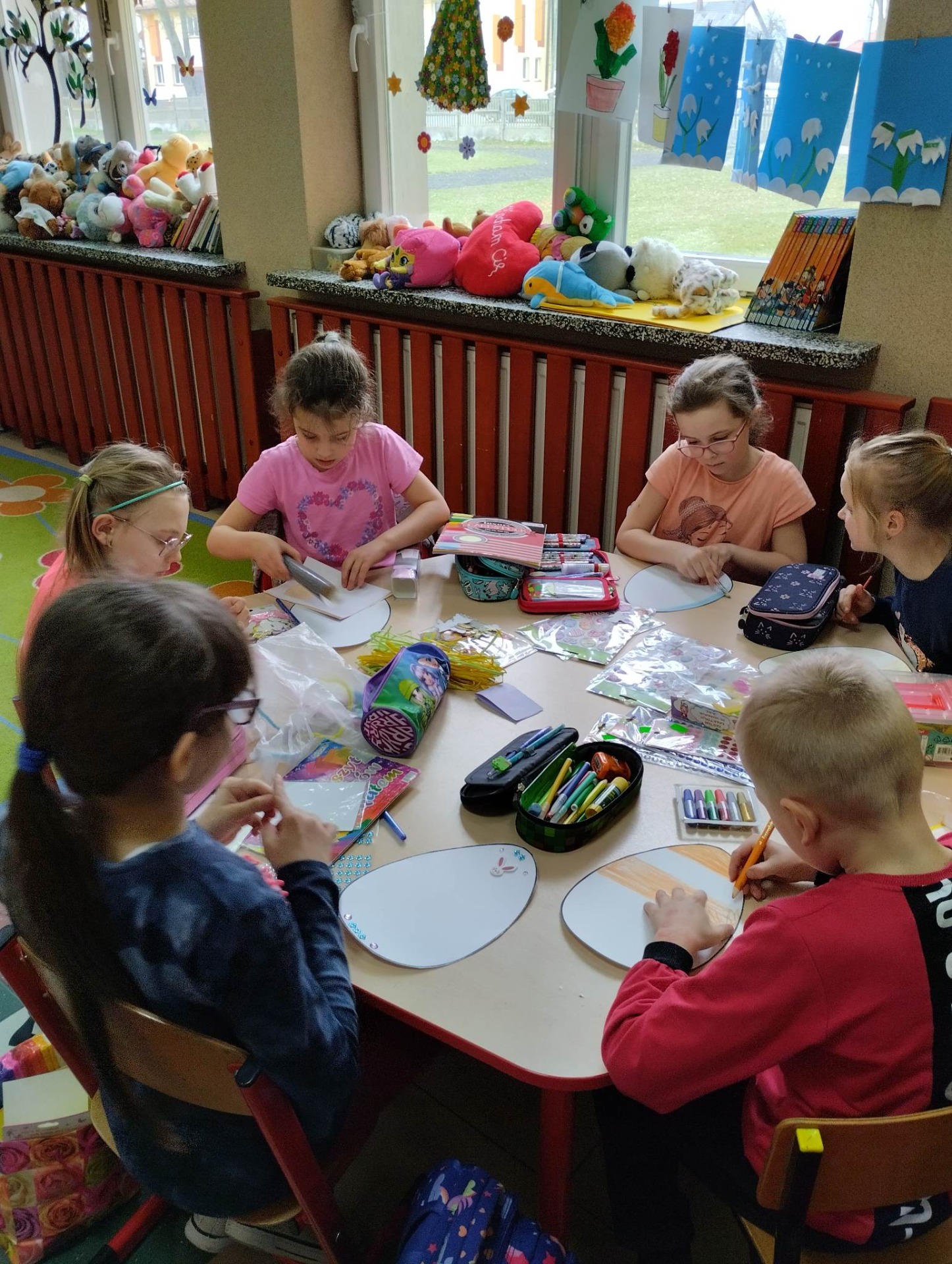 Uczniowie kolorują "ekologiczne pisanki" przy stolikach świetlicowych