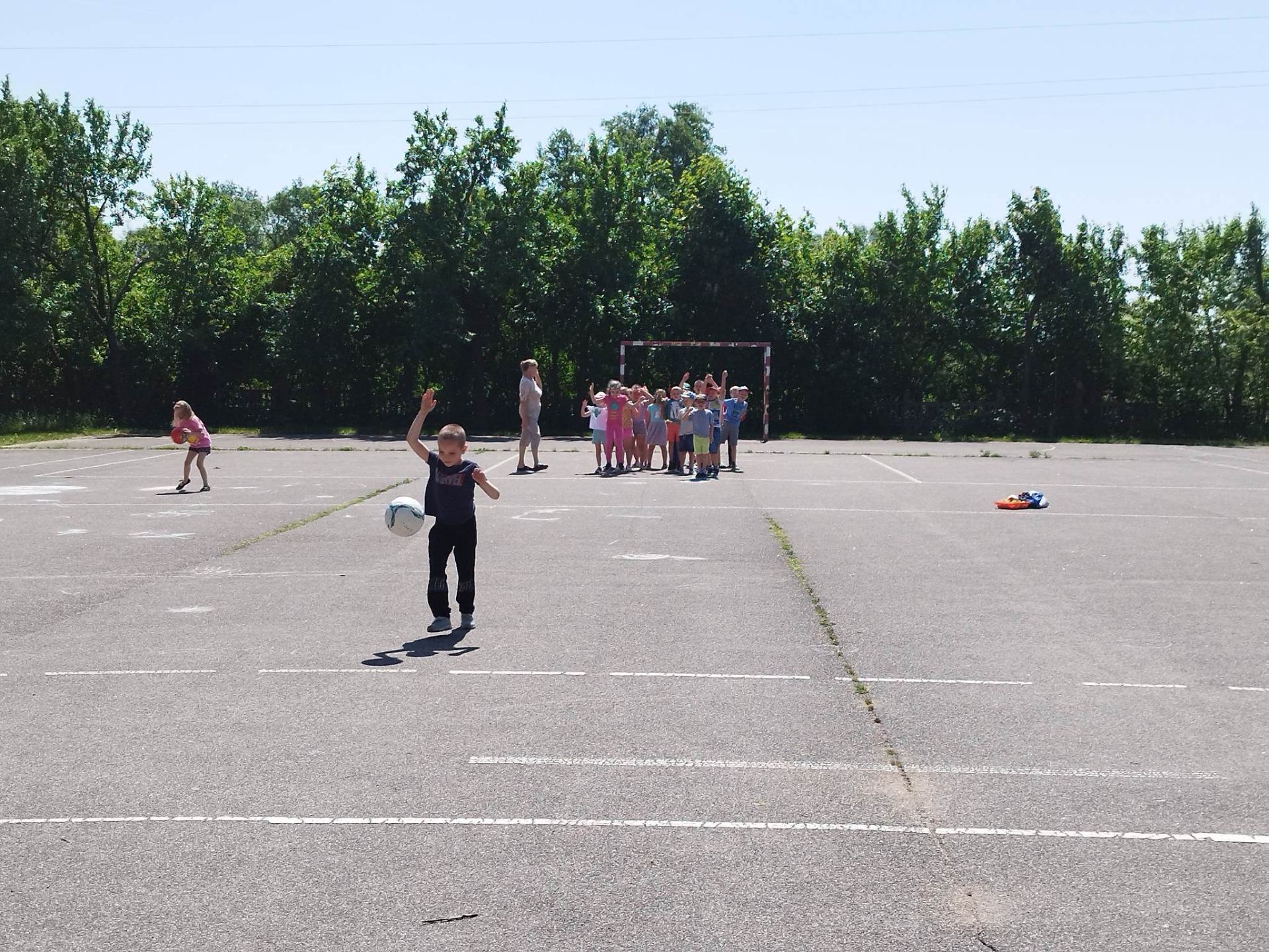 Przedszkolaki biorą udział w zabawach sportowych na szkolnym boisku
