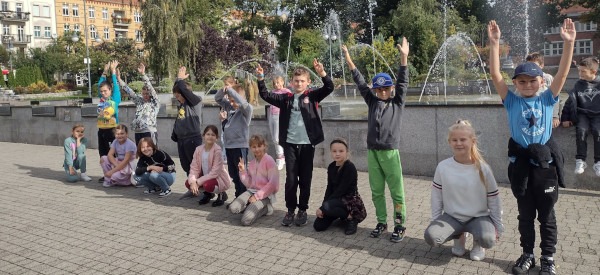 Uczniowie podczas zabawy ruchowej przed fontanną w parku