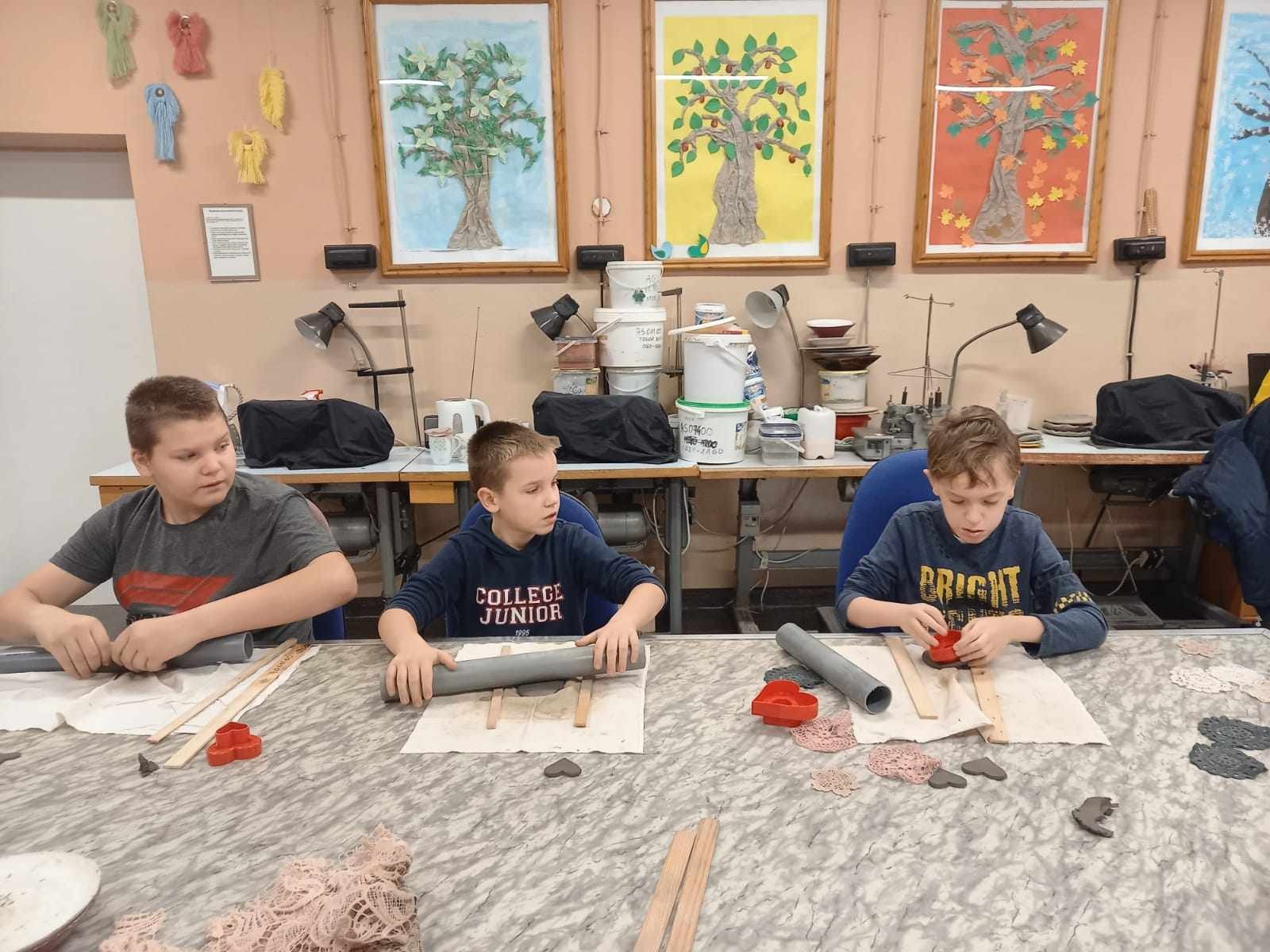 Uczniowie ugniatają glinę na stole. 