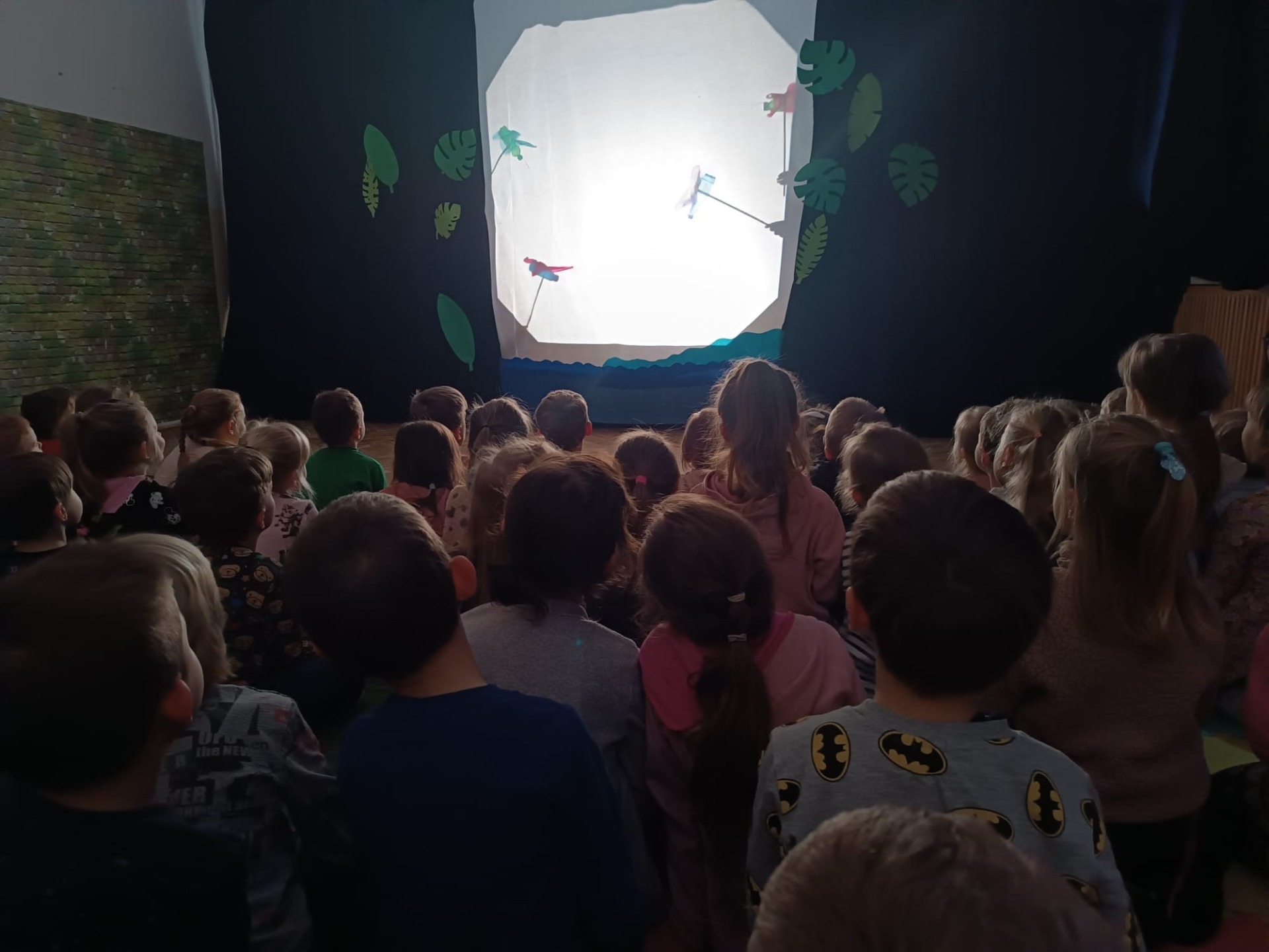 Dzieci z Przedszkola Publicznego Nr 67 "Stokrotka" i Przedszkola Publicznego Nr 23 "Zefirek" oglądają teatr cieni  pt. "Jak mały słonik zawstydził małpy". 