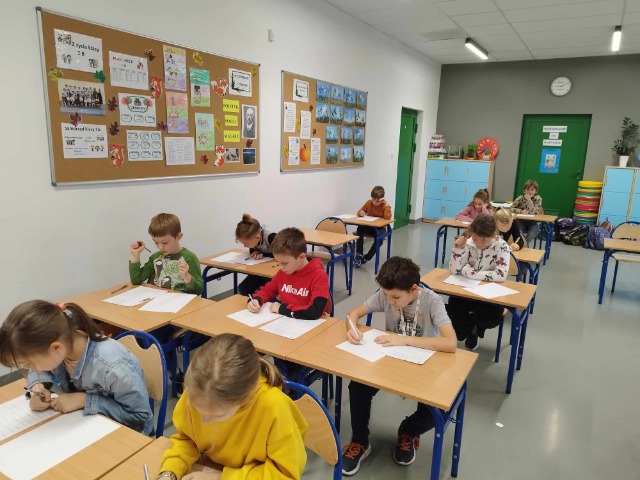 Dzieci w sali lekcyjne rozwiązujące zadania.