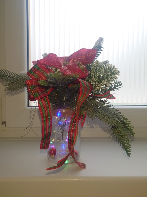 Zaprezentowany wykonany stroik świąteczny, który stoi  na parapecie.
