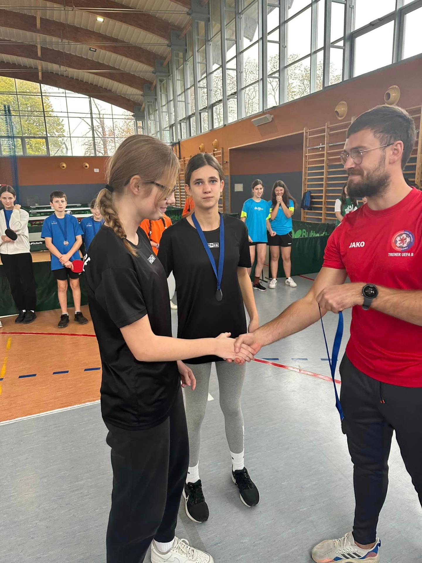 Dominika Paplicka i Laura Świercz otrzymują medale za zajęcie drugiego miejsca w Igrzyskach Młodzieży Szkolnej w tenisie stołowym.