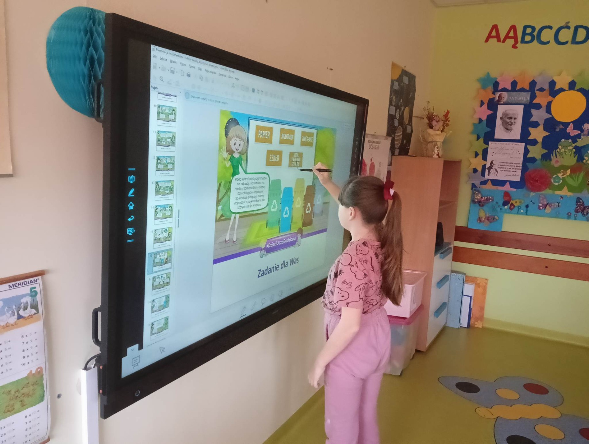 Uczniowie rozwiązują quiz o tematyce ekologicznej na monitorze interaktywnym