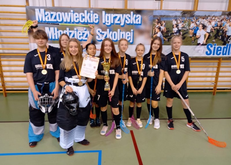 Zdjęcie zbiorowe drużyny dziewcząt unihokeja SP73 ze złotymi medalami, pucharem i dyplomem