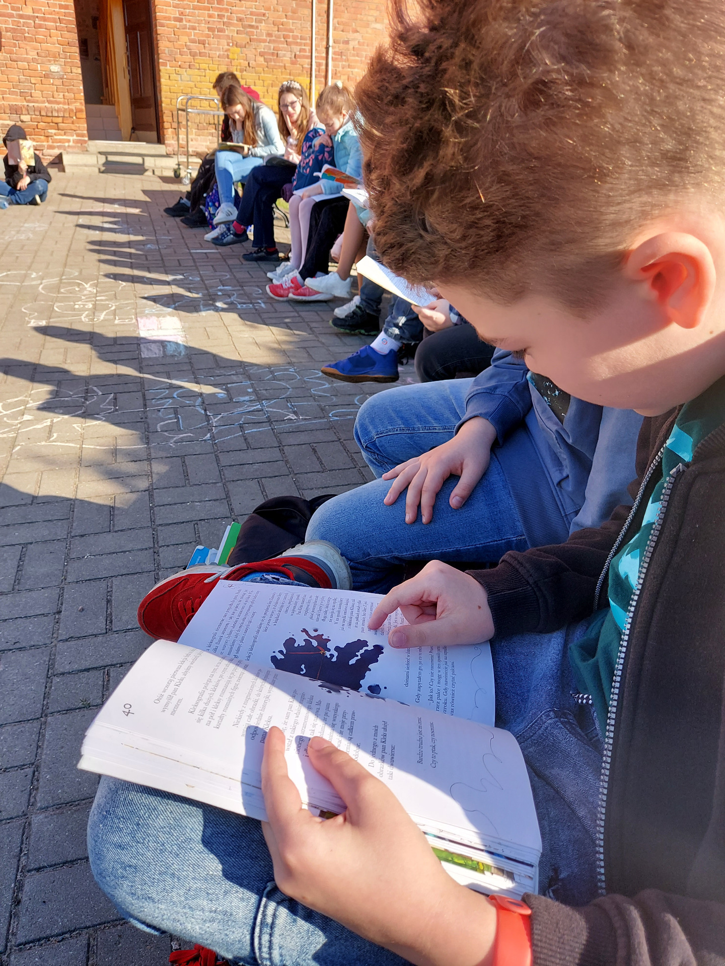 Uczniowie czytają książkę w plenerze