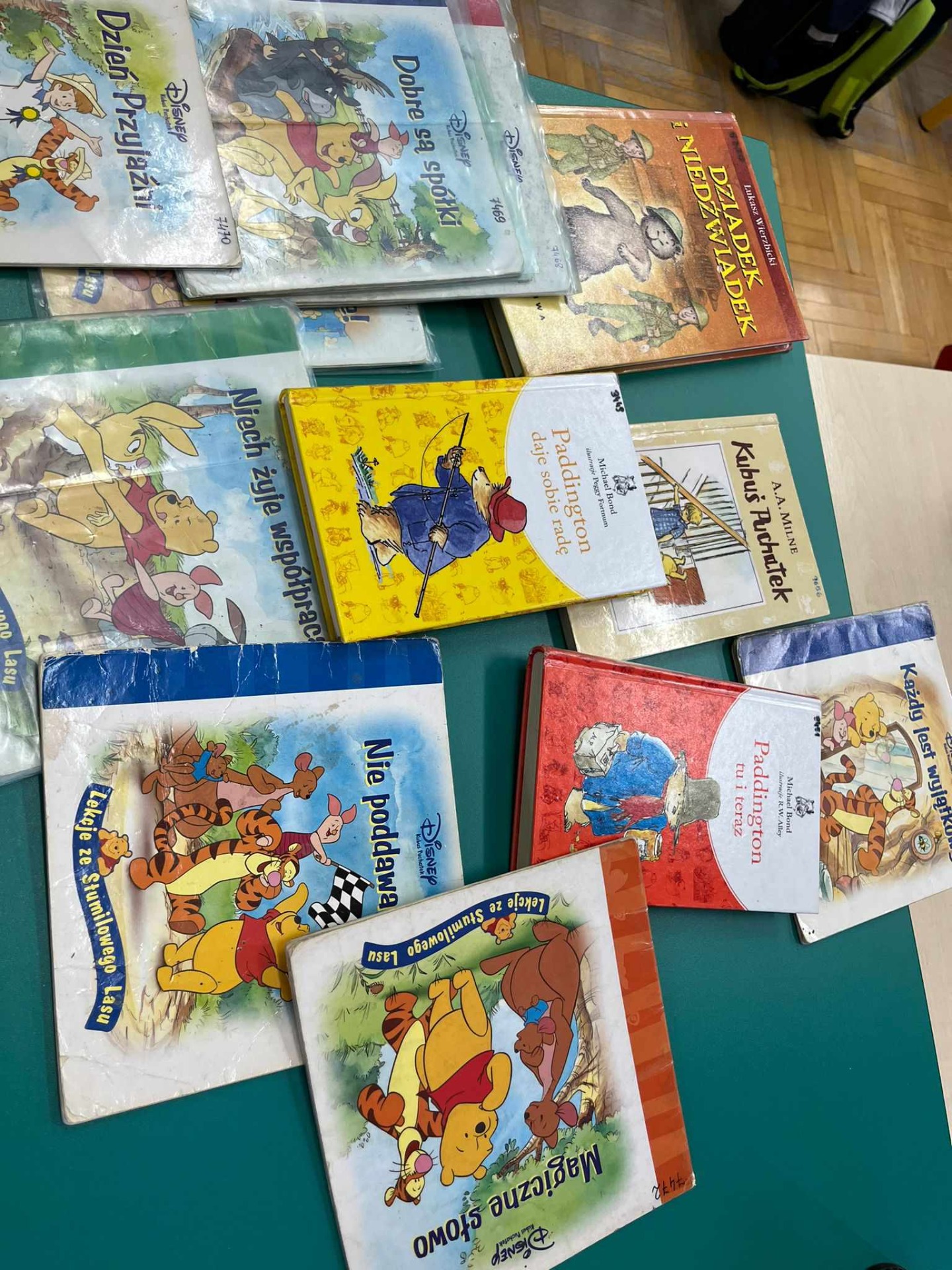 Na stoliku leżą kolorowe książki, których bohaterami są misie: Kubuś Puchatek, Paddington, Kubuś Puchatek i przyjaciele, Dziadek i Niedźwiadek.